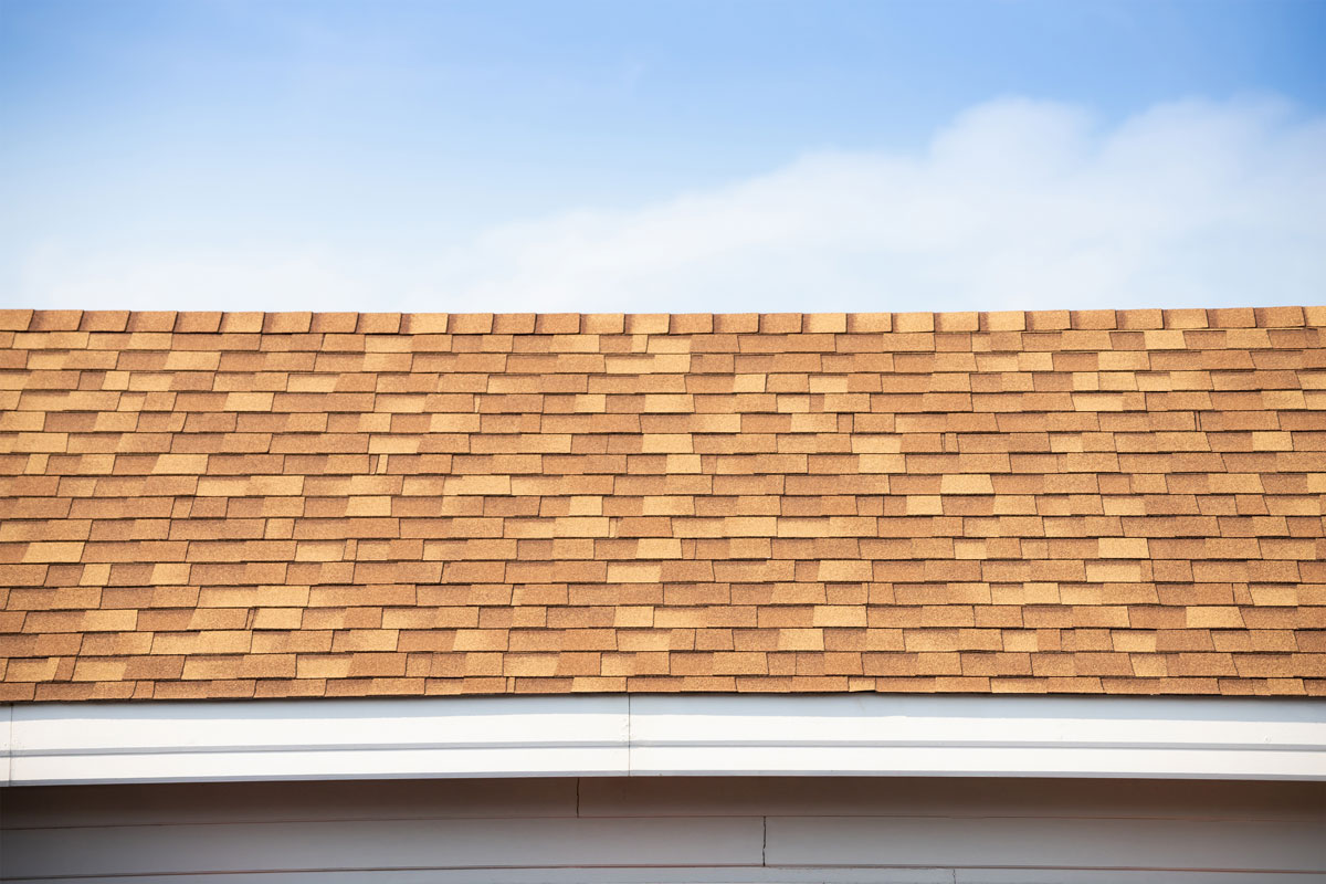 Brown Roof Shingle And Blue Sky. Asphalt Tiles On The Roof