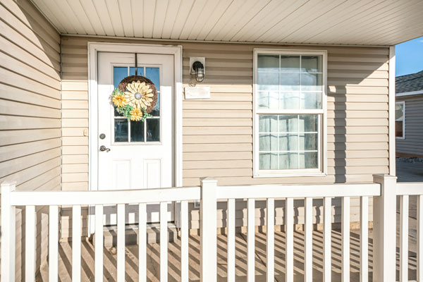 Porch Of A House With Beige Vinyl Wood Siding And Railing